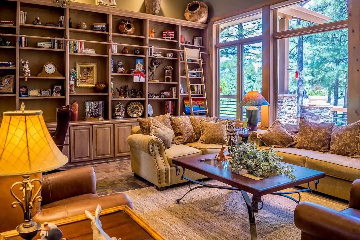 A living room with a large light brown sofa is placed in front of a wooden bookshelf that spans the entire back wall.
